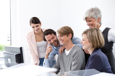 Fröhliches Business Team am Schreibtisch im Büro. Erfolgreiche Zusammenarbeit & Teamwork.