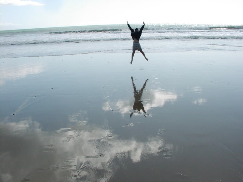 Person springt am Strand, Spiegelung im Wasser. SMART Ziele visualisieren.