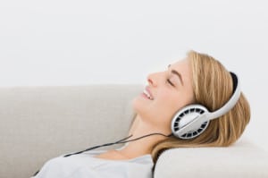 Closeup of a happy young woman lying on sofa and listening to mu