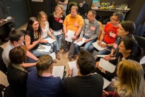  Eine Gruppe von Teilnehmern des NLP Hamburg Workshops sitzt im Kreis und tauscht sich aus.